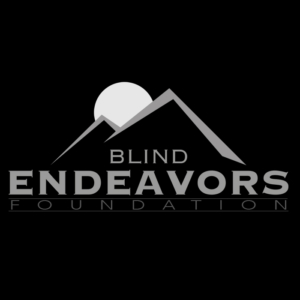 The logo for Blind Endeavors, a black and white image consisting of two mountain peaks with a sun rising between them and the text Blind Endeavors Foundation below the image.